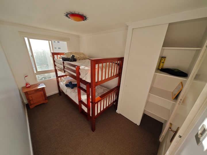 Izba s manželskou posteľou a nočným stolíkom s komodou. 
Skrinka a súprava plážových rakiet a tenisových loptičiek. 