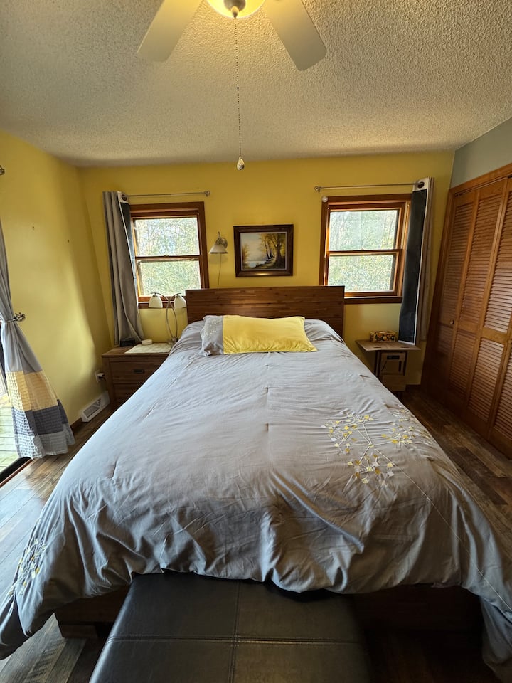 Chambre principale avec salle de bain attenante, vue sur le lac, accès à la terrasse menant au spa.