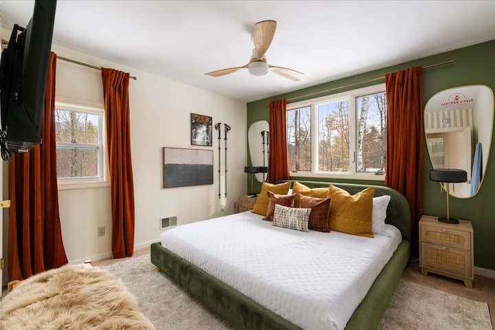 Chambre principale sereine avec lit king size moelleux, vue sur la forêt, ventilateur de plafond et lumière naturelle chaude — conçue pour un sommeil réparateur et ininterrompu.