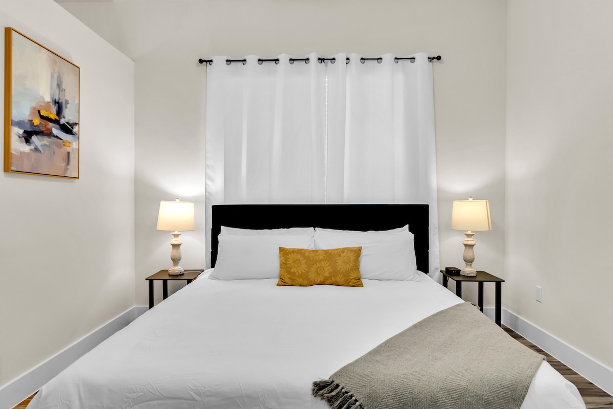 Minimalistická spálňa s pohodlnou posteľou, neutrálnymi tónmi a veľkými oknami s výhľadom.