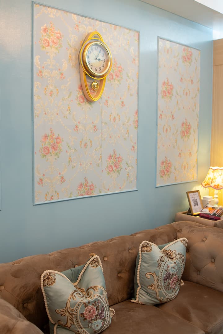 A cozy corner straight out of a period drama. Featuring floral wall panels, vintage accents, and our classic Chesterfield sofa, this elegant nook is perfect for relaxing, reading, watching Netflix or capturing your next favorite photo