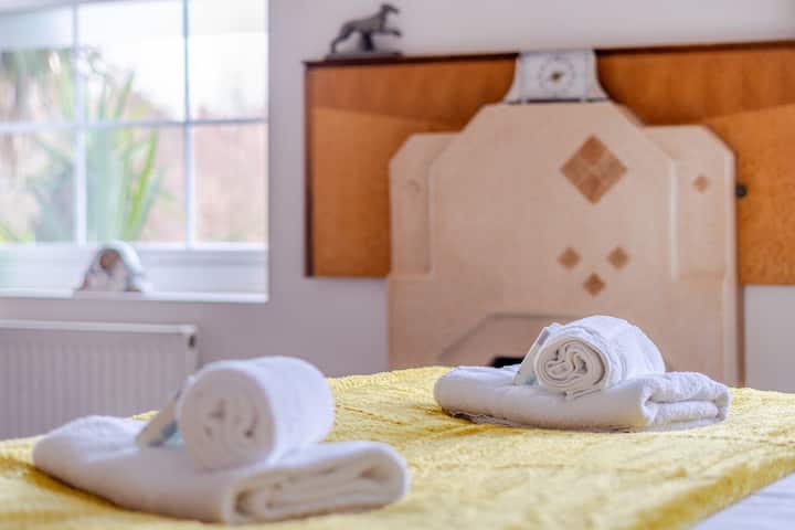 საწოლზე დაწყობილია ახლადგარეცხილი პირსახოცები, რომლებსაც ემატება რბილი ყვითელი ტონები, რომლებიც ოთახს სითბოსა და სინათლეს სძენს. მინიატურული სააბაზანოს ნივთები, რომლებიც დაგეხმარებათ, მყუდროდ დაბინავდეთ