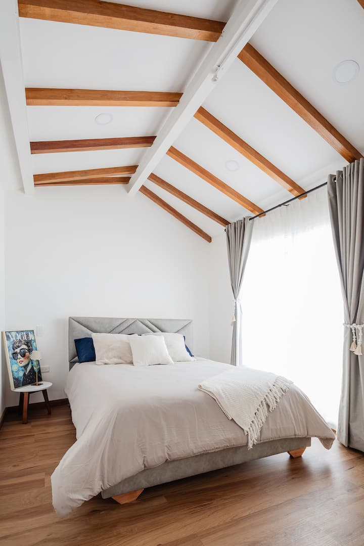 Unwind in an elegant room with a contemporary design, where high ceilings with wooden beams and plenty of natural light create a warm and sophisticated atmosphere. Rest in a comfortable double bed.