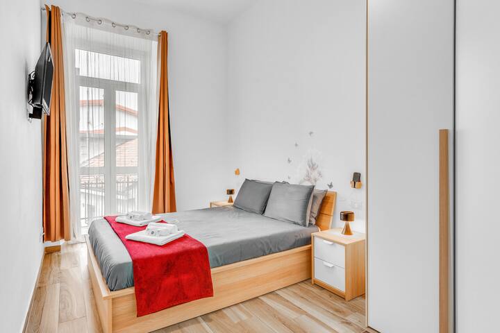 Dormitorio con mesitas de noche, lámparas y soporte para teléfono celular.