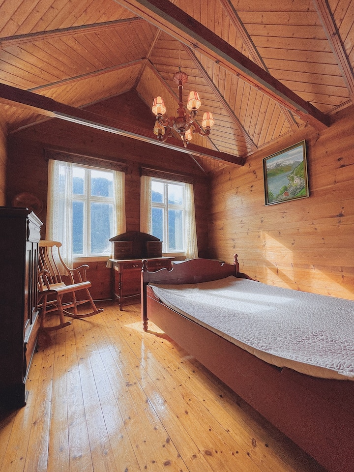 חדר שינה מקסים עם מיטה זוגית, קירות עץ ואווירה חמה ומסורתית.