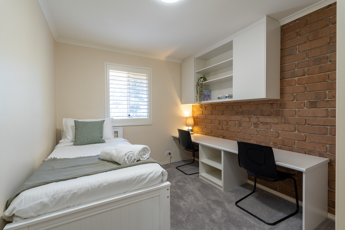 The second bedroom features a single bed, with a second single rollaway bed available if required. The room also includes a dedicated workspace, ideal for guests needing to study or work.