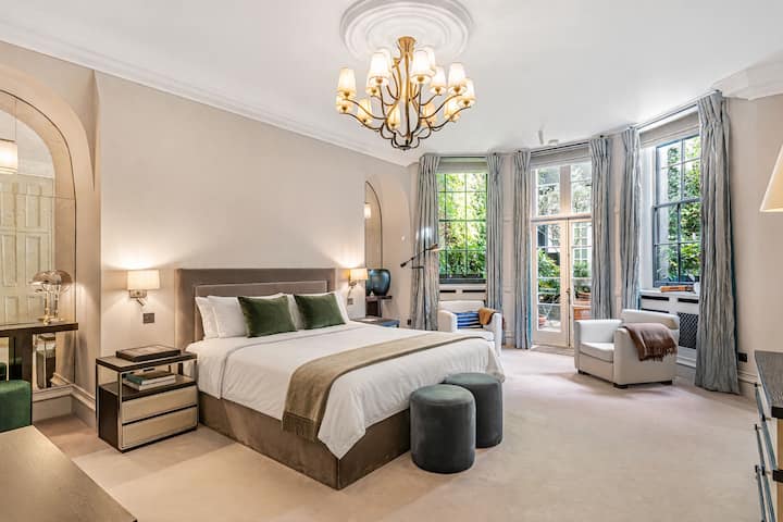 Një dhomë gjumi kryesore luksoze me një krevat dopio "king", një llambadar elegant dhe dritare nga dyshemeja deri në tavan që mbushin hapësirën me dritë natyrale për një pushim vërtet të qetë.