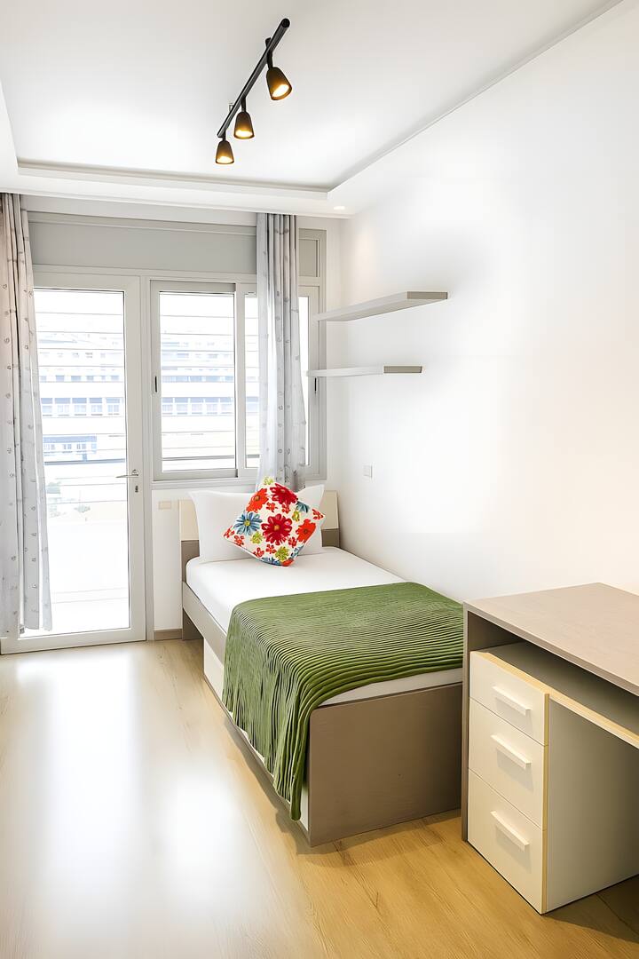 Moderná a svetlá spálňa s balkónom, pohodlnou posteľou a veľkým vstavaným šatníkom. Skvelý priestor na písací stôl na prácu. Sofistikovaná dekorácia s nádychom zelene, parketová podlaha a dizajnové osvetlenie. Kompletný a tichý priestor.