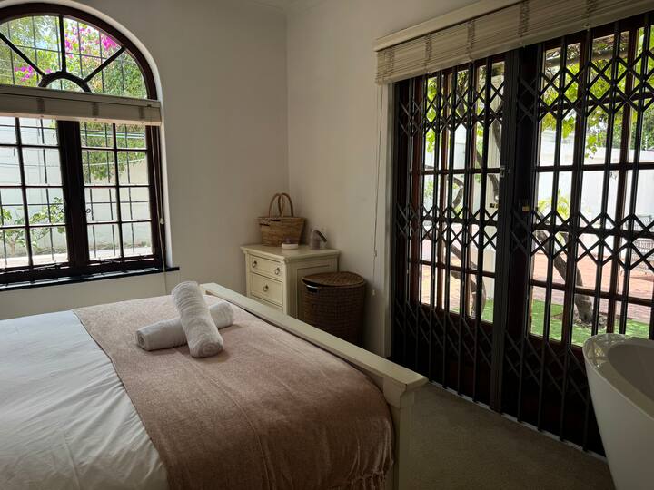 The Main Bedroom doors look out on the beautiful Hout Bay mountains and has a small faux grass patio covered by grape vines.