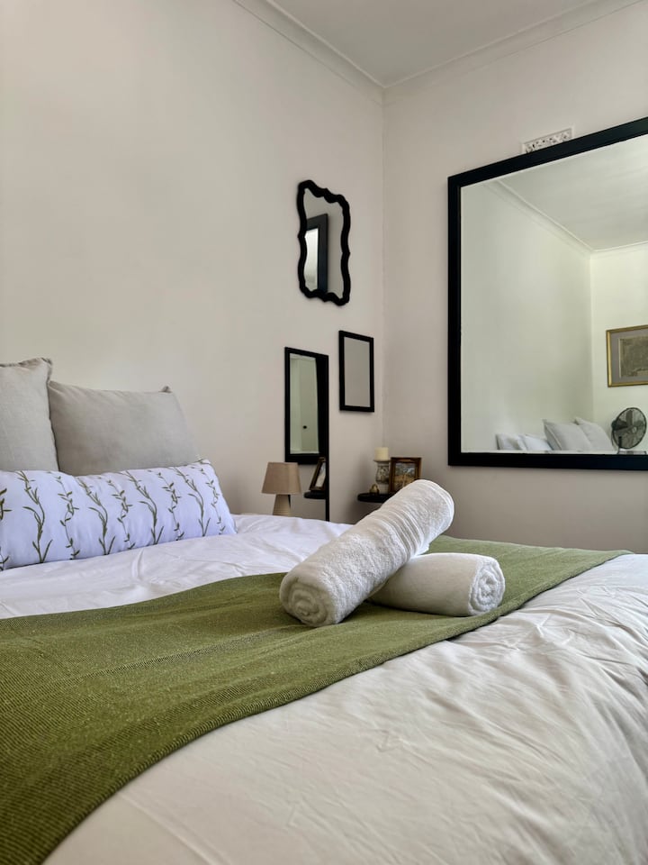 The first bedroom features a queen bed, with soft natural light from the front garden. This bedroom features a wall of mirrors, perfect for getting ready.