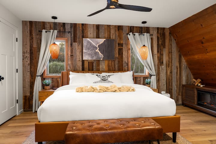 Serene primary suite with a king bed dressed in ultra-comfort, Four Seasons–style bedding. Soft pendant lighting creates a calming glow, with convenient charging stations on both nightstands.  Handsome drapes for dark room sleeping.  