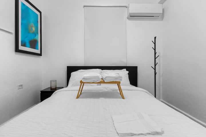 Dormitorio minimalista con cama queen, diseño sobrio y ropa de cama cómoda.