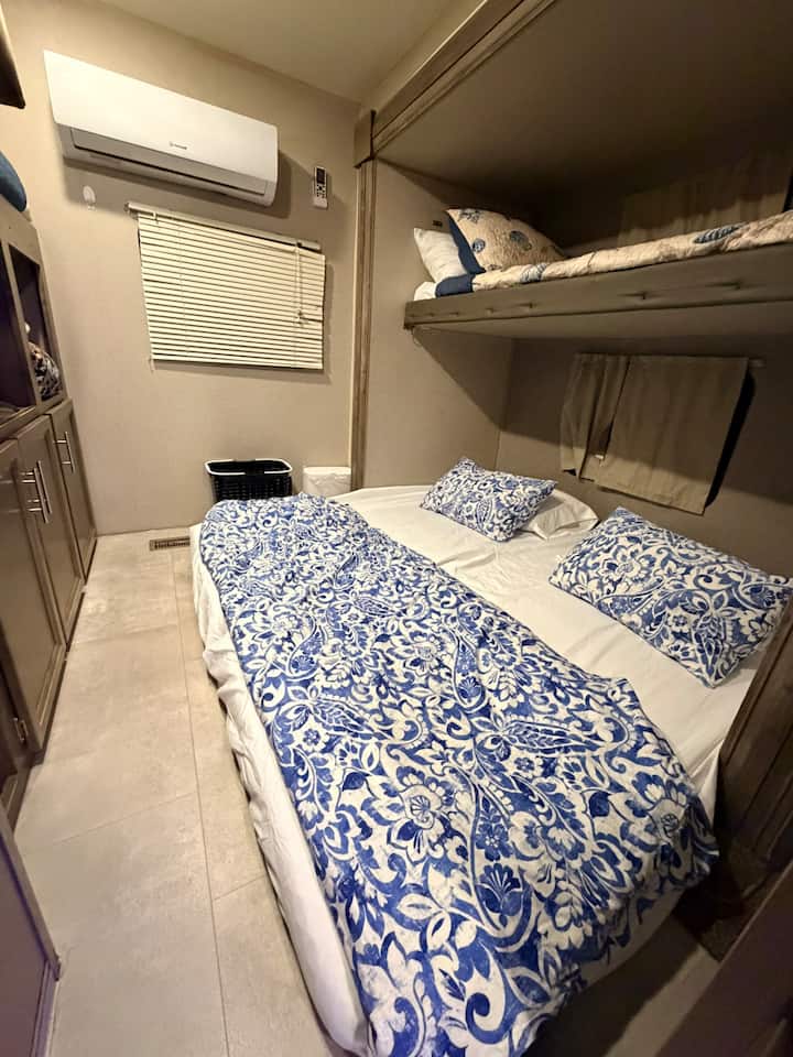 The rear bedroom includes two twin beds, best suited for children, a TV, and a couch that unfolds into a queen-size bed made up of two twin mattresses under one fitted sheet. This bed is directly on the ground. 