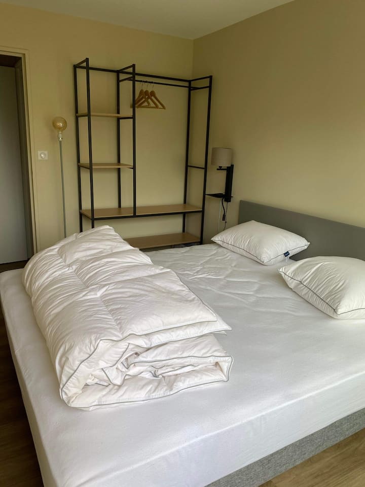 Relaxačná a moderná spálňa s veľkou pohodlnou posteľou, ktorá bude pripravená s posteľnou bielizňou poskytnutou na váš pobyt. Otvorená kovová skrinka ponúka pohodlný úložný priestor.