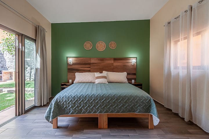 Habitación luminosa con cama King Size y vista al jardín. Cuenta con puerta corrediza de vidrio con mosquitero que permite ventilar el espacio cómodamente. 