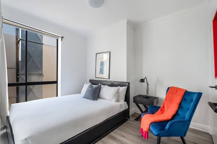 Rust in de tweede slaapkamer, waar een queensize bed, zachte verlichting en een opgeruimde stijl een rustige ruimte bieden om op te laden na een dag in de stad.