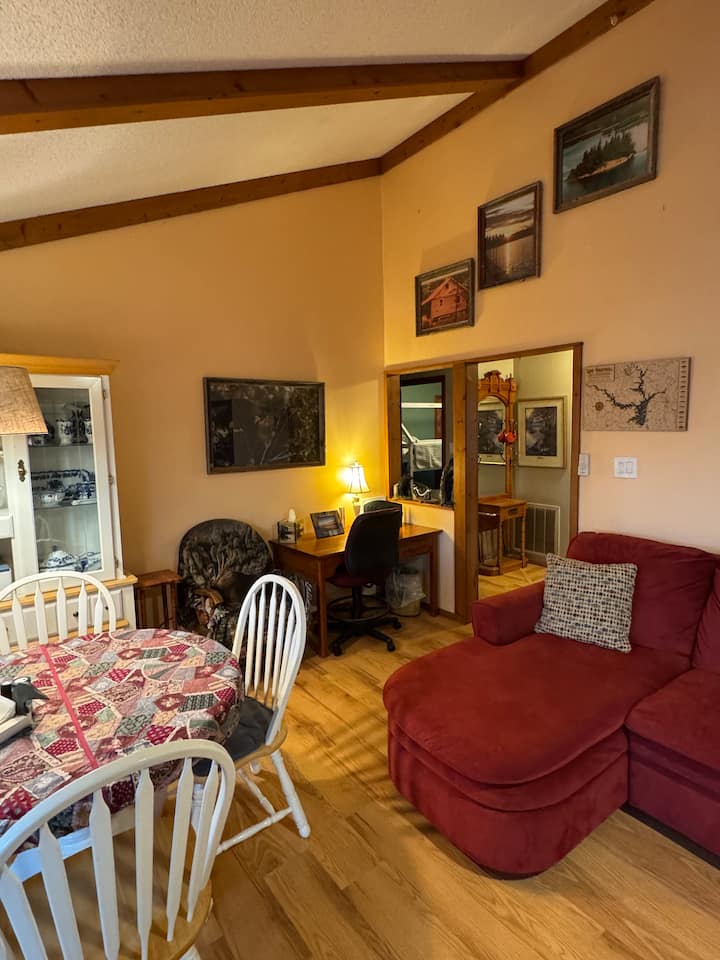 Coin repas avec 4 chaises et une table, grand divan et 3 autres chaises dans le grand salon.