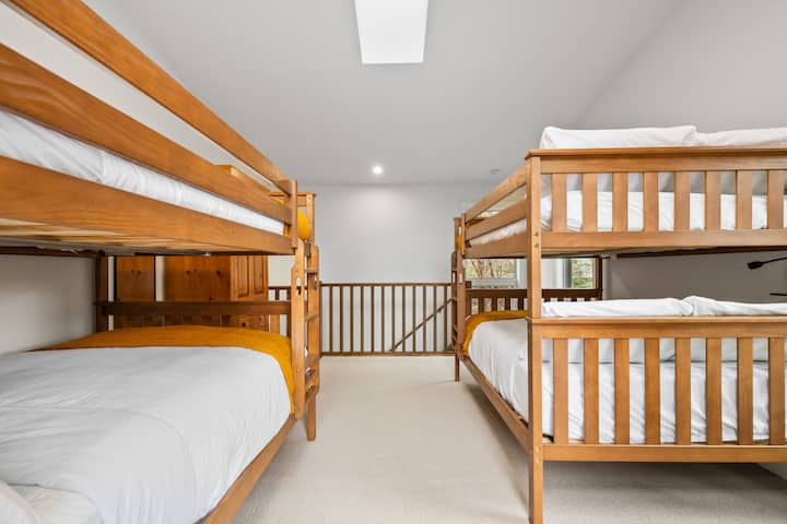 Dormitorio n.º 2 en el piso de arriba con dos camas dobles superpuestas, un televisor inteligente con DVD y Disney+, persianas opacas y acceso directo al patio