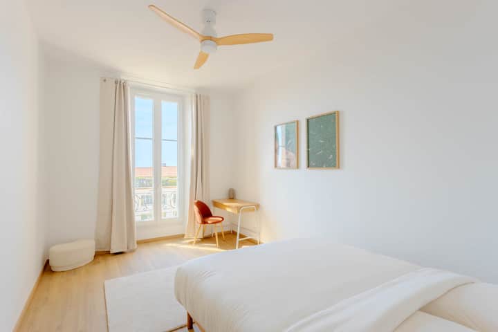 Chambre spacieuse et lumineuse avec lit double, grande fenêtre et petit espace bureau idéal pour télétravailler.