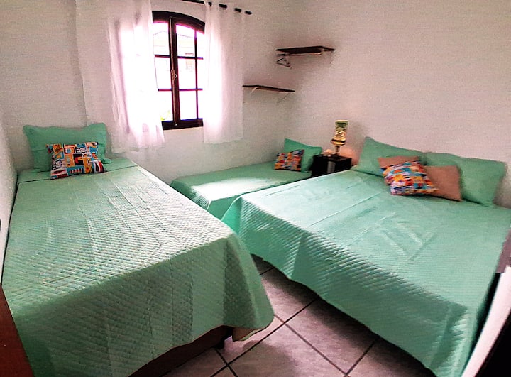 Quarto 3 amplo e flexível, com 2 camas box, 1 cama viúva e 1 auxiliar. Pode ser configurado com 4 camas individuais ou 1 cama de casal + 2 solteiros, acomodando famílias e grupos com conforto e praticidade.