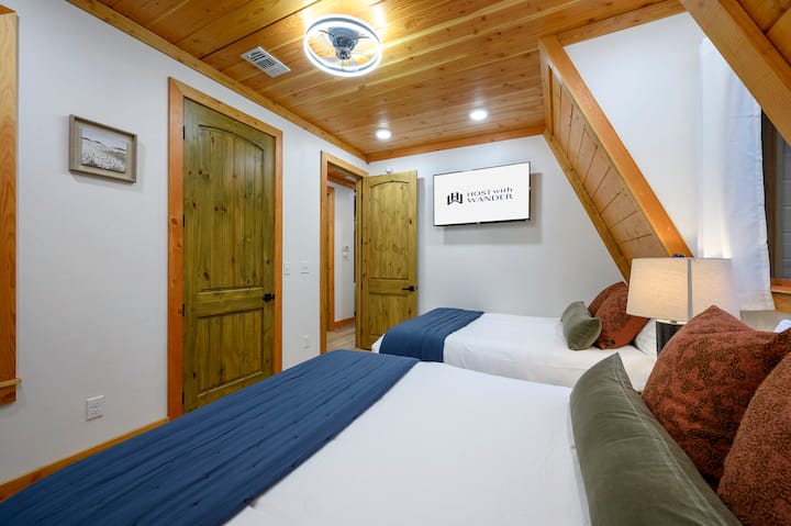 Dos camas tamaño queen con techo de madera y decoración rústica de cabaña en Tahoe in the Pines Broken Bow