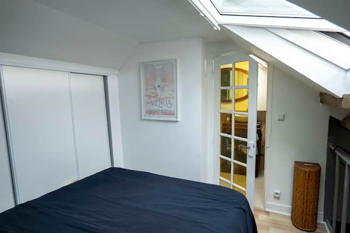 En el altillo, un dormitorio con ventana con vista al cielo y a la Torre Eiffel.