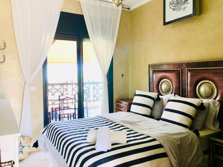 غرفة نوم فاخرة ومشرقة، حيث تلتقي الراحة بالهدوء. استمتع بإطلالات الشرفة وبساتين الزيتون، وهي ملاذ للهدوء.