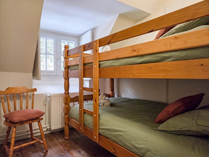 Segundo dormitorio con litera de dos camas individuales, ideal para niños o amigos. Una silla cómoda completa el espacio, y la ventana con radiador aporta luz y calor.