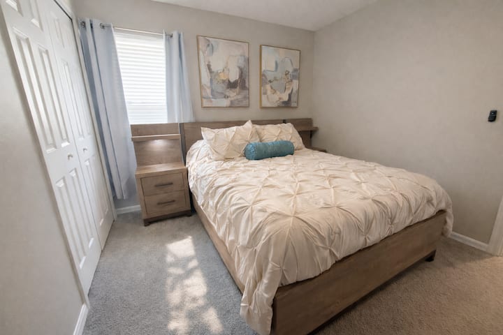 Habitación con cama queen de diseño acogedor, que ofrece luz natural, ventilador de techo y televisor privado.