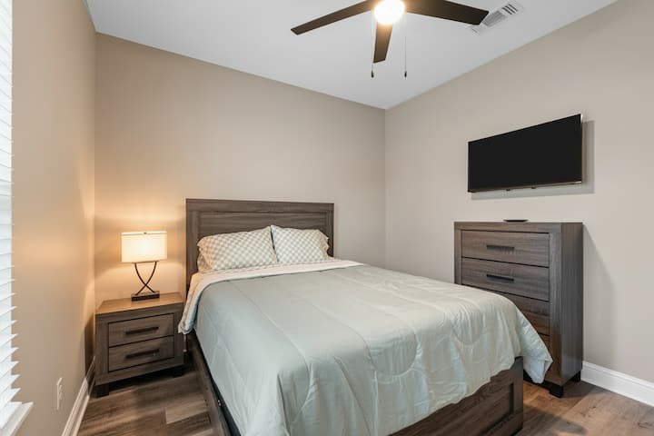 Relájate en este acogedor dormitorio, perfecto para parejas y familias. Disfruta de la iluminación suave de la lámpara de cabecera y del entretenimiento en el televisor montado en la pared. Un ventilador de techo garantiza comodidad durante todo el año. 