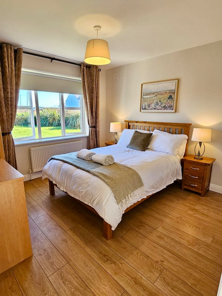 חדר שינה כפול מואר ונוח עם נוף לגינה, תאורה רכה ומצעים איכותיים ללילה של מנוחה.