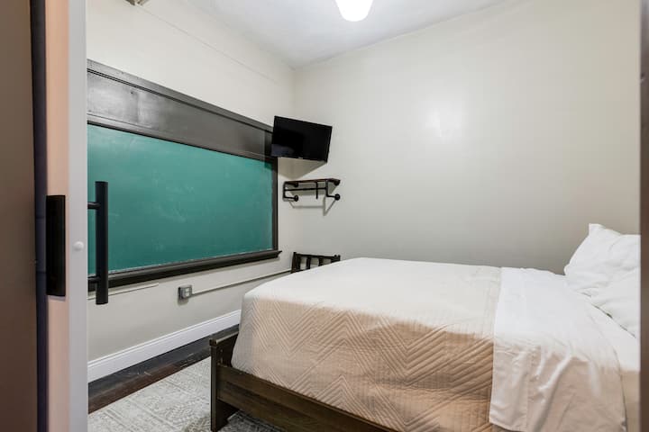 We call this our chalkboard room. It is cozy with a queen-size bed, bedside tables, plug-ins for devices, and the only bedroom with an original chalkboard.
