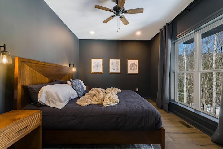 Moody tones and warm wood finishes give this bedroom a cozy, elevated feel that is perfect for unwinding.