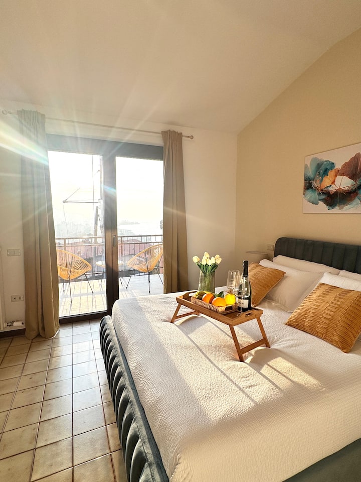 Tweepersoonskamer met een ruime keuze aan kussens, toegang tot de toonbank met uitzicht op het Lago Maggiore en de stad Luino