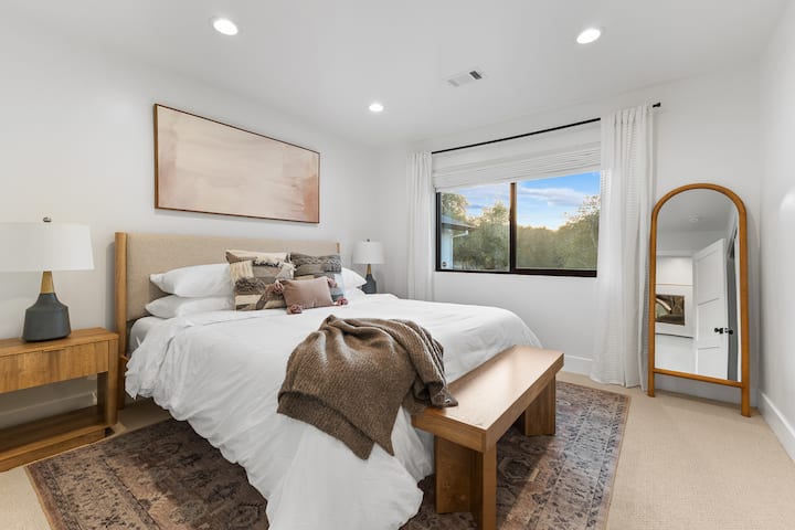 Unwind in our cozy, elegantly designed bedroom, complete with plush bedding, a scenic view, blackout shades and a warm, welcoming atmosphere.