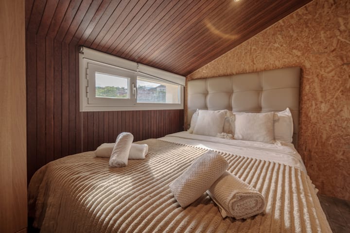 Dormitorio abuhardillado con techo de madera.