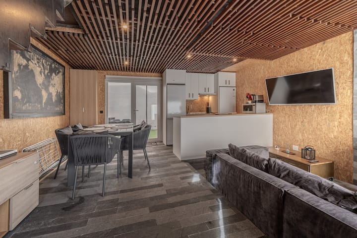 Comedor junto a la cocina, con TV y salida al jardín.