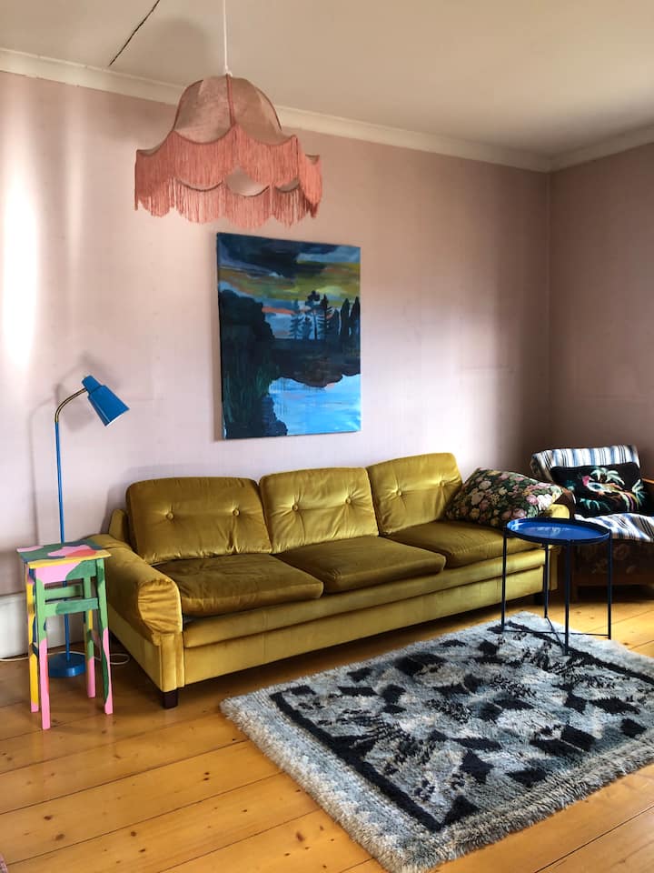 Sala de estar con sofá cama individual, sillones, sillas y piano vertical.
