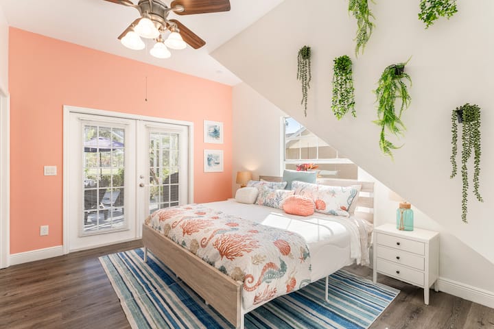 Dormitorio de invitados con cama tamaño king, medio baño adjunto y puertas francesas que se abren al lanai.