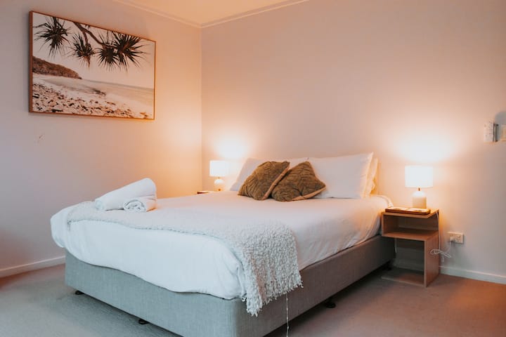 Habitación con cama tamaño queen, una cálida iluminación ambiental, ropa de cama de calidad y un relajante ambiente costero