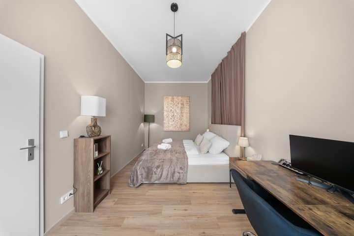 Das Herzstück der Wohnung: Schlafzimmer 1 empfängt Sie direkt vom Eingang. Geräumig, ruhig und komfortabel eingerichtet – mit TV, Stehlampe und allem für eine entspannte Auszeit.