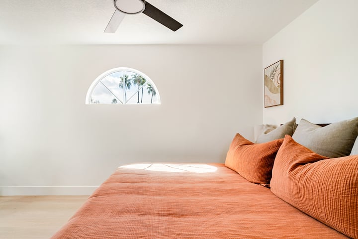 Wake up to beautiful views through this unique arched window in a guest bedroom styled with warm, inviting desert tones.