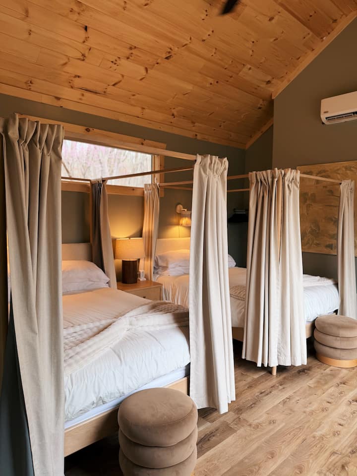 Two queen beds with privacy curtains, soft lighting, and a warm, well-designed space that offers comfort along with a sense of separation when needed.

Cozy linens, blackout curtains & shades, air purifier, a ceiling fan and sound machine.
