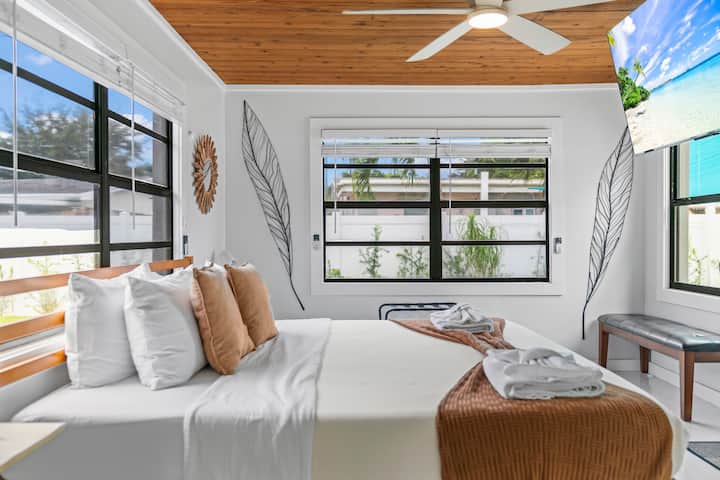 Morning light through three windows and the wood plank ceiling overhead. The primary earns its name.