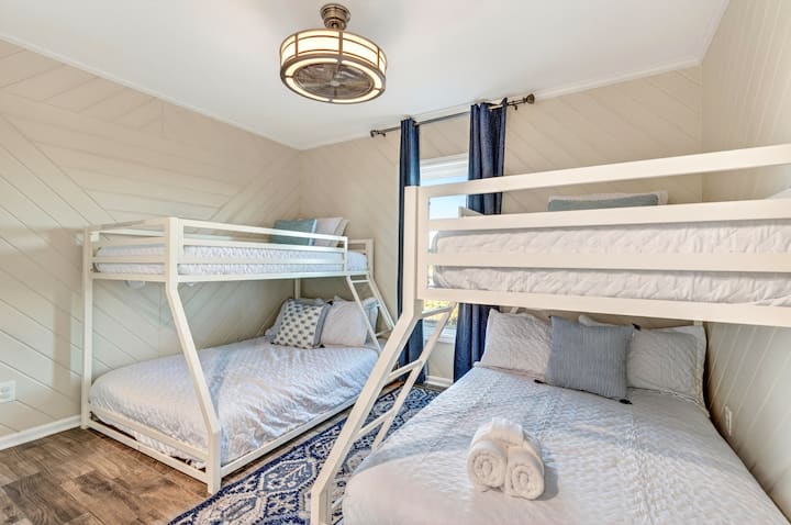 Este luminoso dormitorio de la planta superior ofrece mucho espacio para dormir, con una litera y una cama queen, ideal para familias.