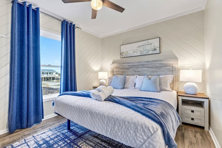 Este luminoso dormitorio principal ofrece impresionantes vistas al agua y cuenta con un ventilador de techo para mantener el ambiente fresco mientras duerme.