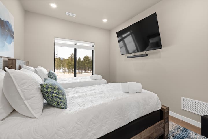 เพลิดเพลินกับยามเย็นในห้องนอนสว่างสดใสพร้อมทีวีติดผนัง หน้าต่างบานใหญ่ และการตกแต่งที่ทันสมัย