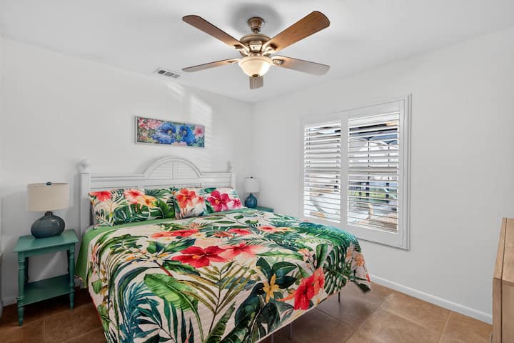 חדר שינה נוח לאורחים עם מיטת קינג סייז, מאוורר תקרה ועיצוב טרופי - אידיאלי לשנת לילה שלווה.