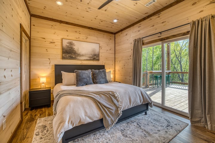 Chambre avec lit King Size et salle de bain attenante au niveau inférieur, avec télévision intelligente, accès à la terrasse et vue sur la montagne.