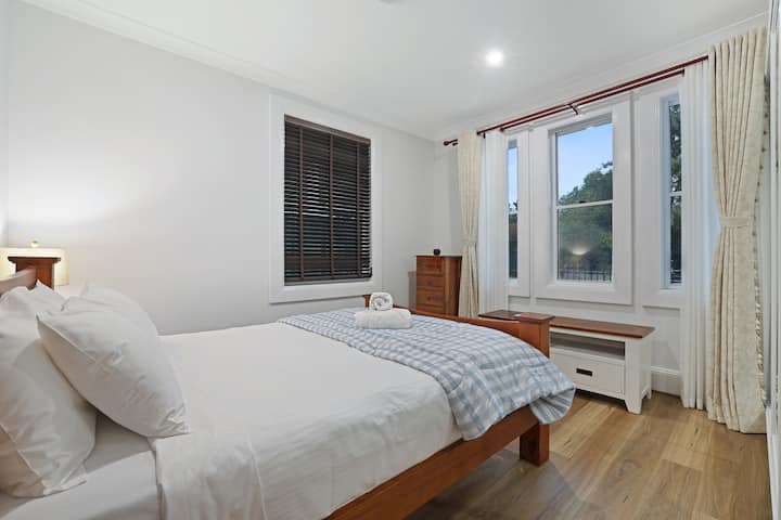 Bright and comfortable main bedroom with storage and full height curtains.